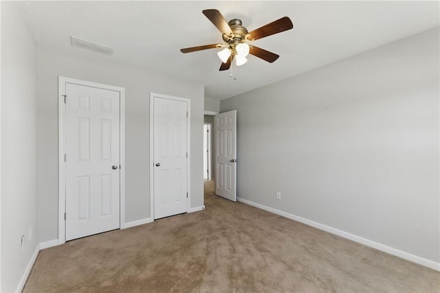 unfurnished bedroom featuring ceiling fan, carpet, visible vents, and baseboards