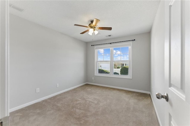 empty room with carpet, visible vents, ceiling fan, a textured ceiling, and baseboards