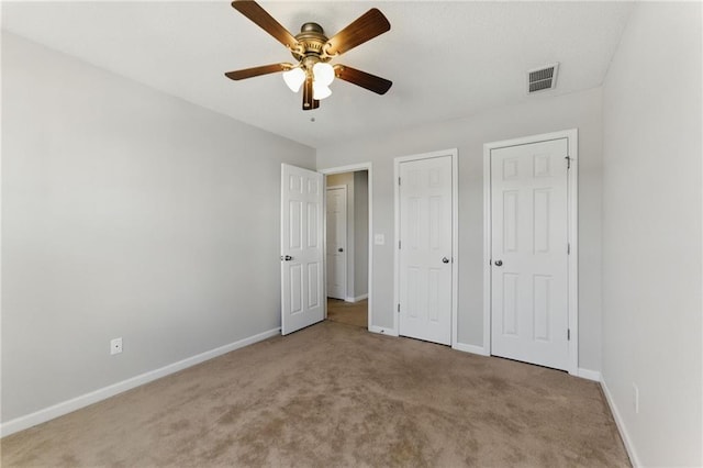 unfurnished bedroom featuring multiple closets, visible vents, a ceiling fan, carpet flooring, and baseboards