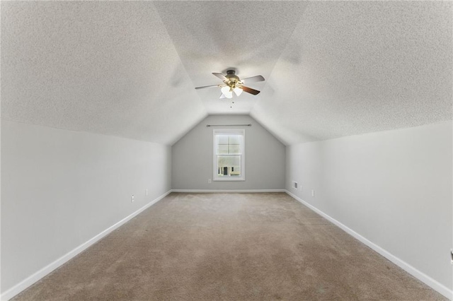 additional living space with lofted ceiling, light carpet, a textured ceiling, and baseboards