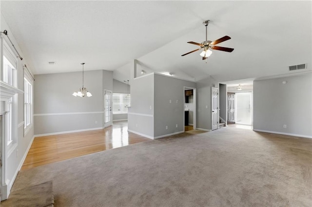 unfurnished living room with light carpet, baseboards, visible vents, vaulted ceiling, and ceiling fan with notable chandelier