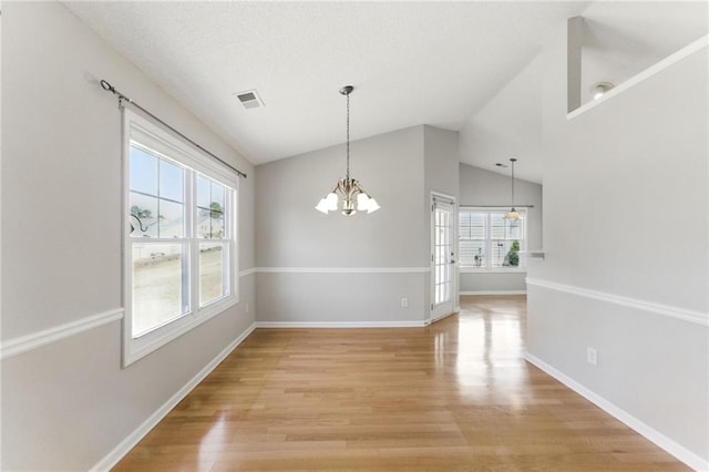 unfurnished dining area featuring lofted ceiling, visible vents, an inviting chandelier, light wood-style floors, and baseboards