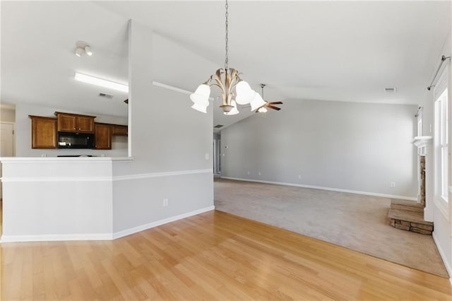 unfurnished living room with vaulted ceiling, light wood-type flooring, baseboards, and an inviting chandelier