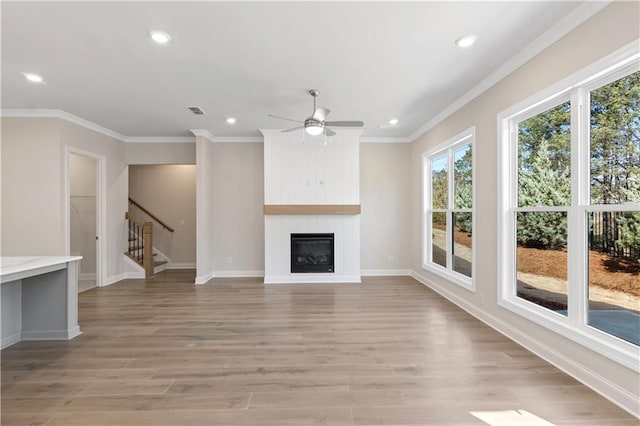 unfurnished living room with light wood-type flooring, a fireplace, ornamental molding, and ceiling fan