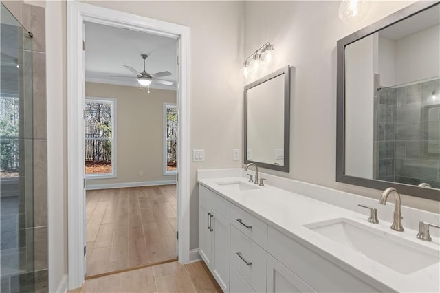 bathroom with wood-type flooring, tiled shower, vanity, and ceiling fan