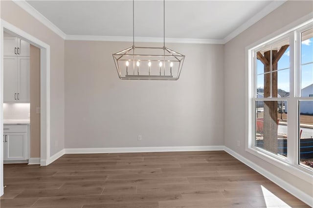 unfurnished dining area with an inviting chandelier, crown molding, and hardwood / wood-style floors