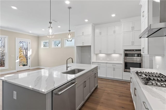 kitchen with white cabinetry, an island with sink, wall chimney exhaust hood, stainless steel appliances, and sink