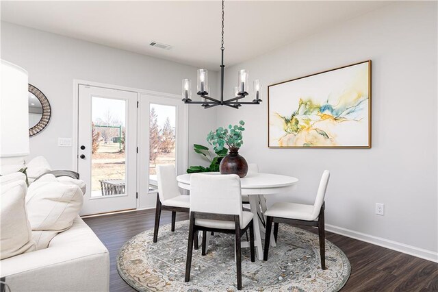 dining area featuring baseboards, dark wood finished floors, visible vents, and an inviting chandelier