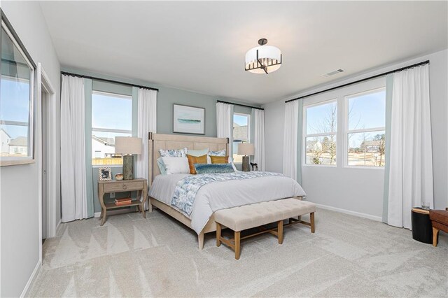 carpeted bedroom featuring visible vents, baseboards, and multiple windows