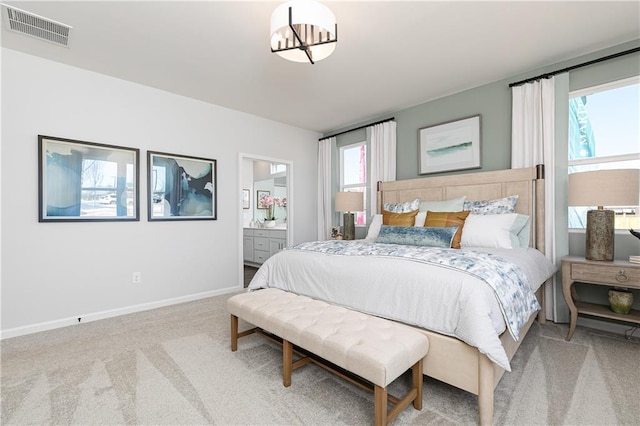 carpeted bedroom with ensuite bath, visible vents, and baseboards