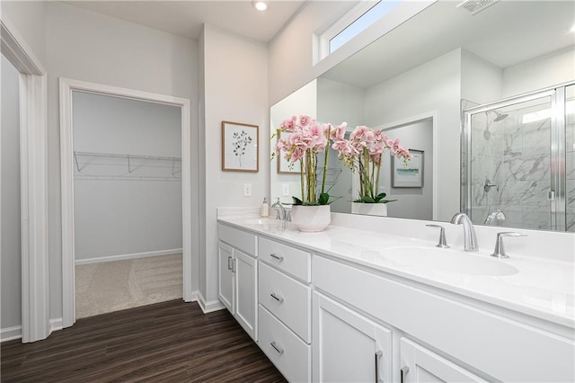 full bath featuring a spacious closet, double vanity, a sink, and a shower stall