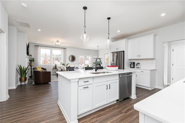 kitchen with stainless steel appliances, light countertops, visible vents, open floor plan, and a sink