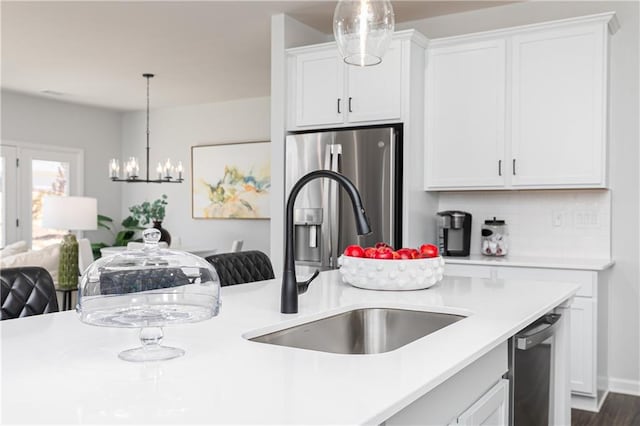 kitchen featuring pendant lighting, stainless steel appliances, light countertops, white cabinetry, and a sink