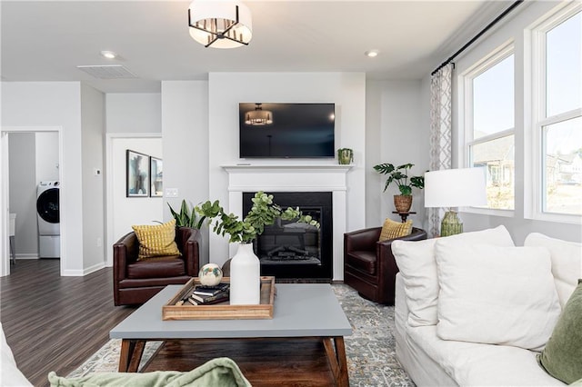 living room featuring recessed lighting, washer / clothes dryer, a glass covered fireplace, wood finished floors, and baseboards