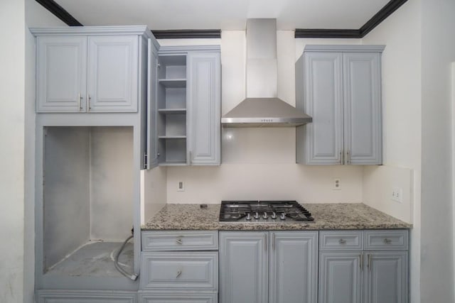 kitchen with crown molding, wall chimney range hood, light stone countertops, stainless steel gas cooktop, and open shelves