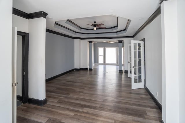 spare room with dark wood finished floors, french doors, baseboards, a raised ceiling, and ornate columns