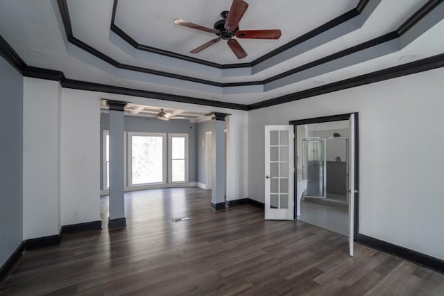 spare room with a tray ceiling, ornamental molding, french doors, ornate columns, and dark wood-style flooring