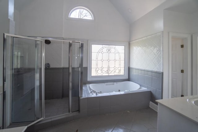 bathroom featuring tile patterned flooring, a tub with jets, a shower stall, and vaulted ceiling