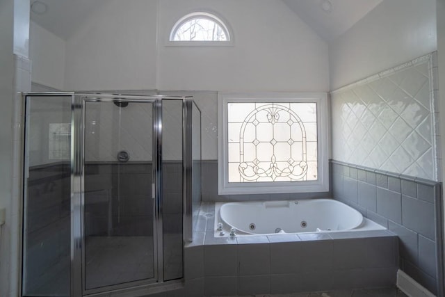 full bathroom with vaulted ceiling, a jetted tub, and a shower stall