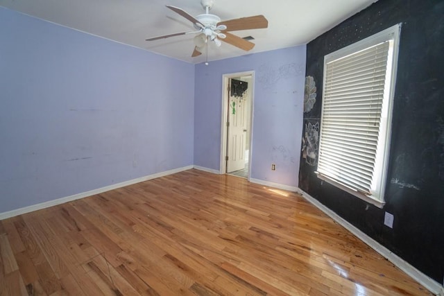 empty room with baseboards, wood finished floors, and a ceiling fan