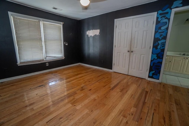 unfurnished bedroom with visible vents, a ceiling fan, a sink, light wood-style floors, and baseboards