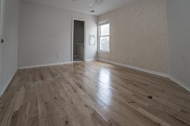 unfurnished room featuring a ceiling fan, visible vents, wood finished floors, and baseboards