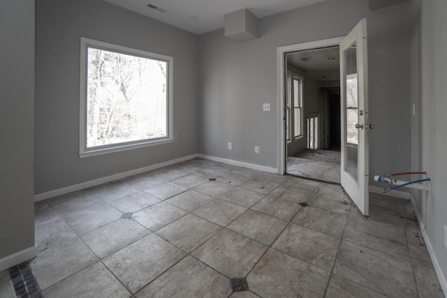 tiled spare room featuring baseboards and visible vents