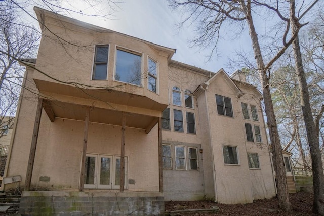 view of side of home featuring stucco siding, french doors, and a chimney