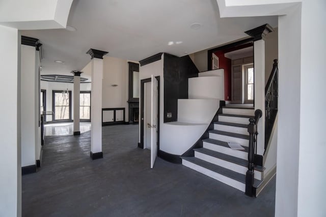 stairway with a healthy amount of sunlight, baseboards, and decorative columns