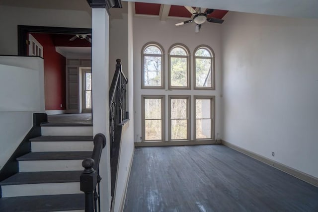 foyer entrance with wood finished floors, a high ceiling, baseboards, ceiling fan, and stairs