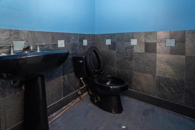 bathroom with a sink, toilet, tile walls, and wood finished floors