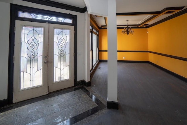 foyer featuring a notable chandelier, ornamental molding, stone tile flooring, french doors, and baseboards