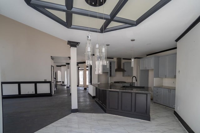 kitchen with marble finish floor, gray cabinets, a sink, dark stone counters, and wall chimney range hood