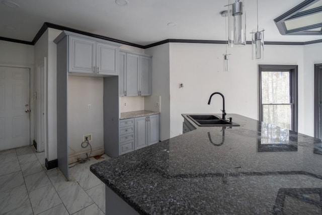 kitchen with marble finish floor, ornamental molding, a sink, dark stone countertops, and hanging light fixtures