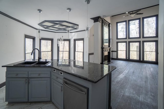 kitchen with a sink, open floor plan, dark stone countertops, and ornamental molding