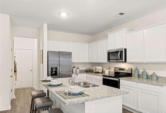339 Elgin Dr, Lawrenceville, GA 30045 - kitchen featuring white cabinets, a kitchen breakfast bar, a sink, dark wood-style flooring, and appliances with stainless steel finishes