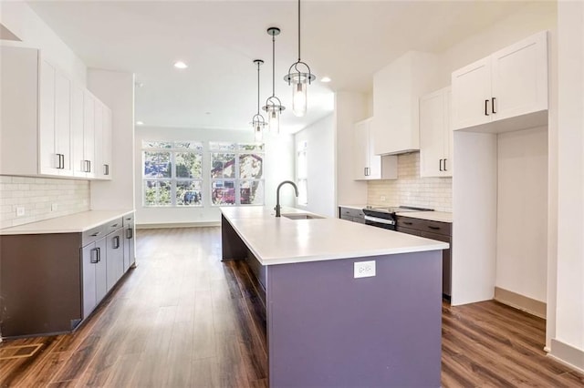 kitchen with white cabinetry, a center island with sink, electric stove, decorative light fixtures, and sink