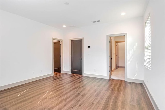 unfurnished bedroom featuring ensuite bathroom and light hardwood / wood-style flooring