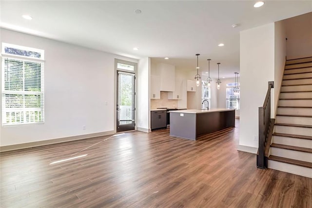 kitchen with a healthy amount of sunlight, pendant lighting, white cabinetry, and a center island with sink