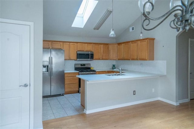 kitchen with light hardwood / wood-style floors, sink, stainless steel appliances, and kitchen peninsula