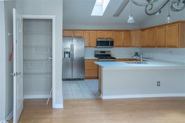 kitchen with pendant lighting, sink, appliances with stainless steel finishes, backsplash, and vaulted ceiling with skylight