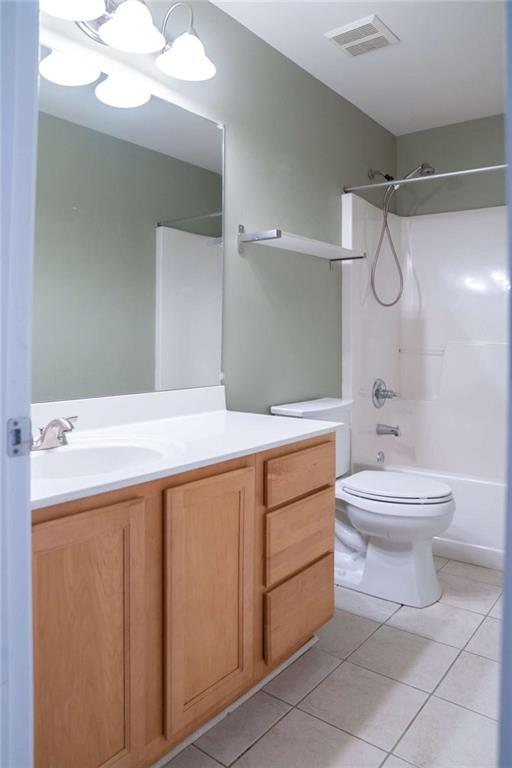 full bathroom featuring washtub / shower combination, toilet, an inviting chandelier, vanity, and tile patterned flooring