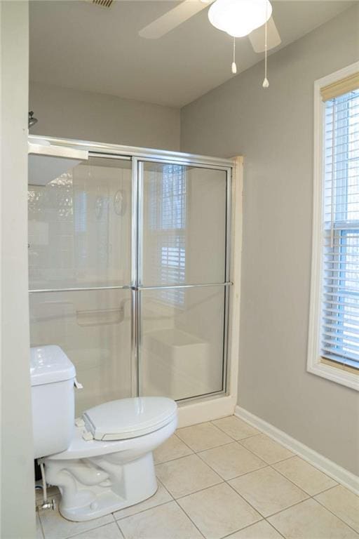 bathroom featuring ceiling fan, toilet, a shower with shower door, and tile patterned flooring