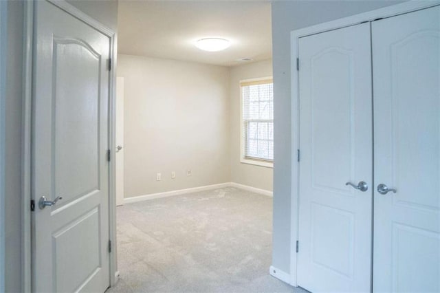 unfurnished bedroom with a closet and light carpet