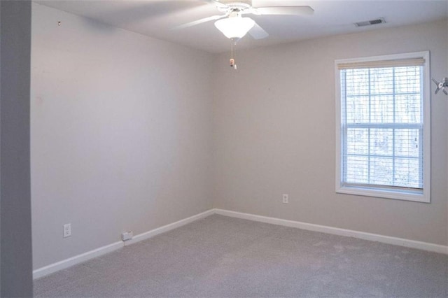 carpeted spare room featuring a wealth of natural light and ceiling fan