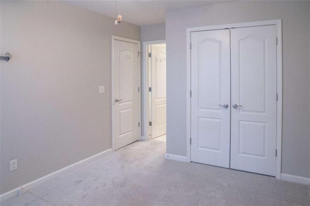 unfurnished bedroom with light colored carpet and a closet