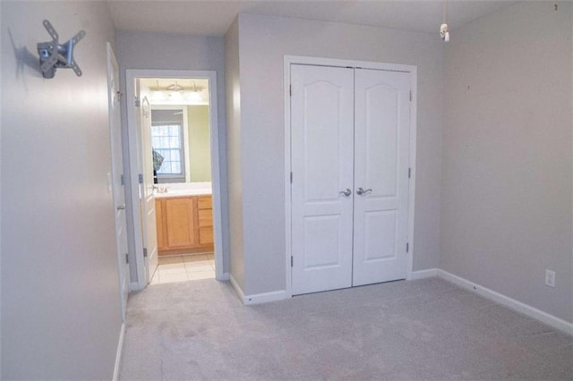 unfurnished bedroom featuring light colored carpet, connected bathroom, and a closet