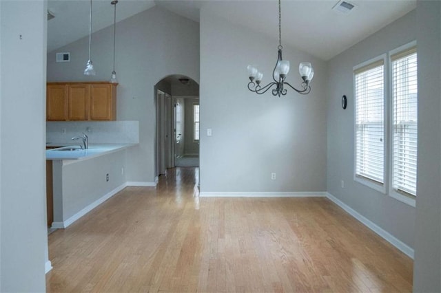 unfurnished dining area with sink, high vaulted ceiling, a healthy amount of sunlight, and light wood-type flooring