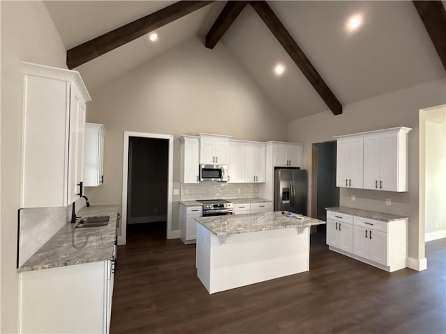 kitchen featuring beamed ceiling, stainless steel appliances, white cabinetry, and a kitchen island