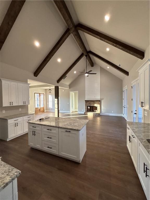 kitchen with white cabinets, beam ceiling, dark hardwood / wood-style floors, and a fireplace